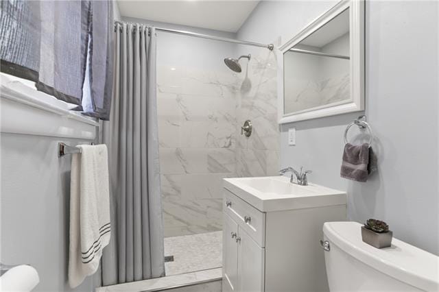 bathroom featuring a tile shower, vanity, and toilet