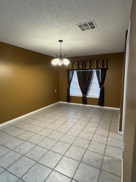 unfurnished dining area featuring light tile patterned flooring, a textured ceiling, and an inviting chandelier