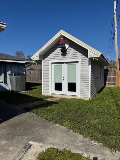 view of outdoor structure with central AC, a yard, and french doors