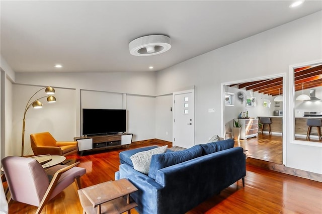 living room featuring wood-type flooring and vaulted ceiling