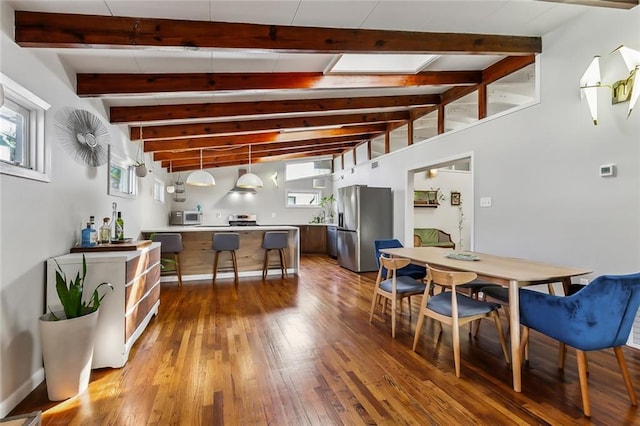 kitchen featuring vaulted ceiling with beams, stainless steel fridge, plenty of natural light, pendant lighting, and hardwood / wood-style flooring