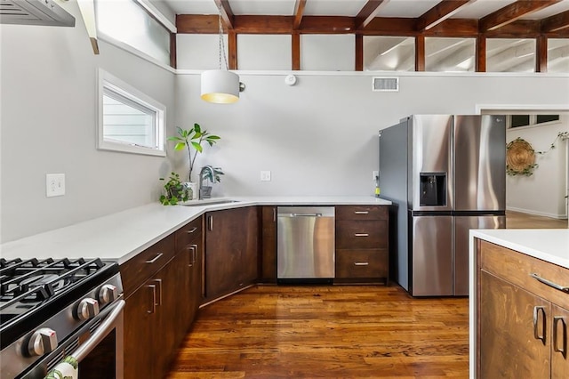 kitchen with hanging light fixtures, sink, dark hardwood / wood-style floors, appliances with stainless steel finishes, and dark brown cabinets