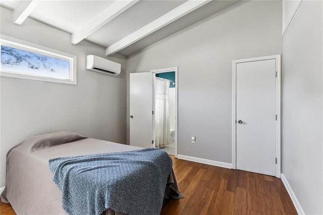 bedroom featuring a wall mounted air conditioner, dark hardwood / wood-style flooring, vaulted ceiling with beams, and ensuite bath