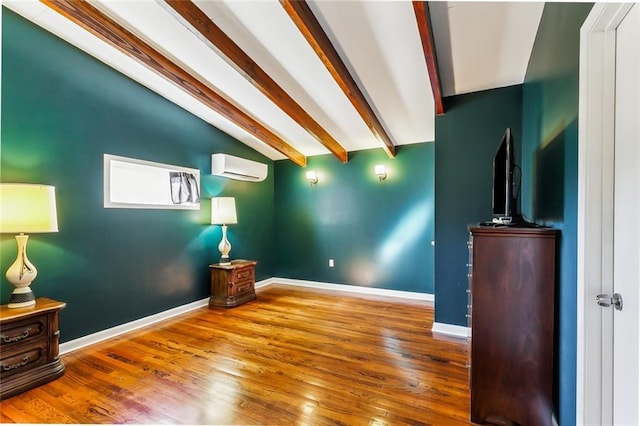 interior space with a wall mounted AC, lofted ceiling with beams, and hardwood / wood-style flooring