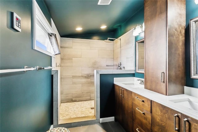 bathroom featuring tile patterned floors, vanity, and a tile shower