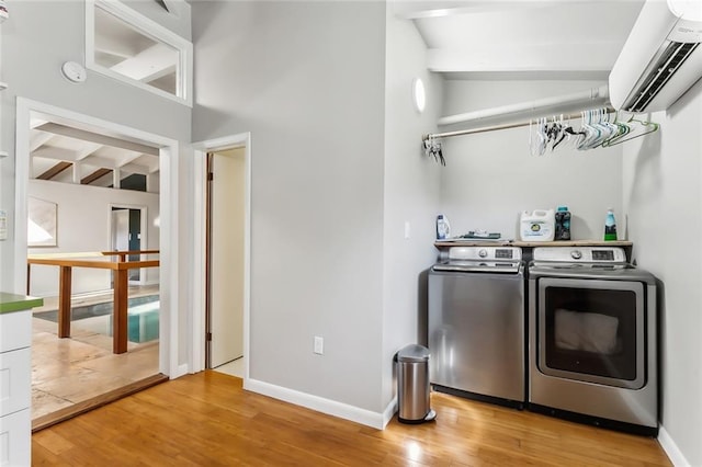 laundry area with hardwood / wood-style floors, washing machine and dryer, and a wall unit AC