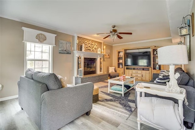 living room with hardwood / wood-style flooring, a brick fireplace, ceiling fan, and ornamental molding