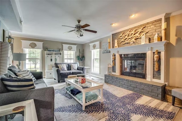 living room featuring a fireplace, light wood-type flooring, ceiling fan, and ornamental molding