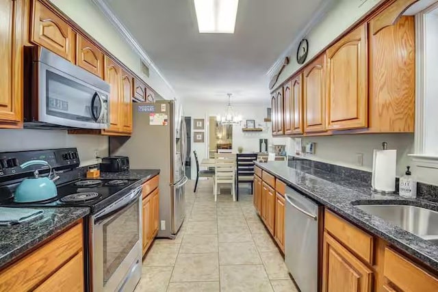 kitchen featuring light tile patterned floors, ornamental molding, appliances with stainless steel finishes, decorative light fixtures, and a chandelier