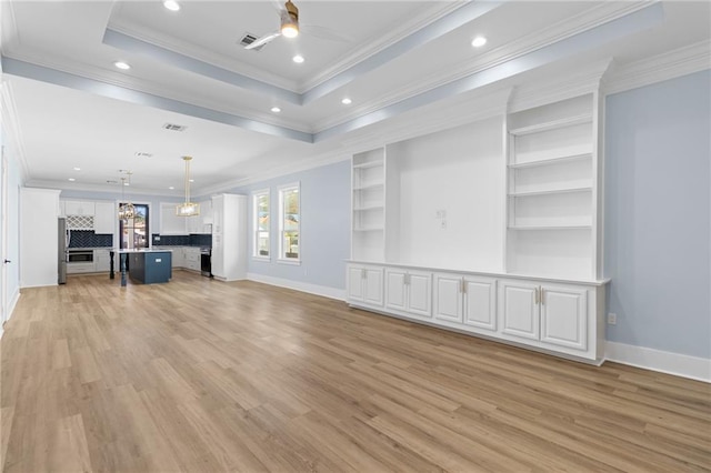 unfurnished living room featuring ceiling fan, light hardwood / wood-style floors, a raised ceiling, and crown molding