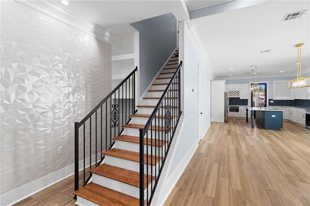 stairs with crown molding and wood-type flooring