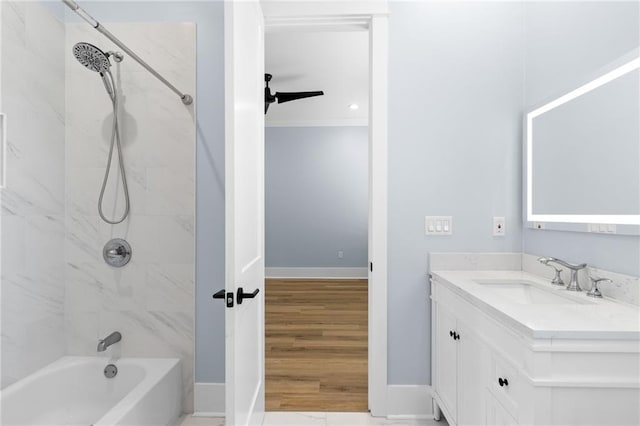 bathroom with ceiling fan, vanity, and tiled shower / bath