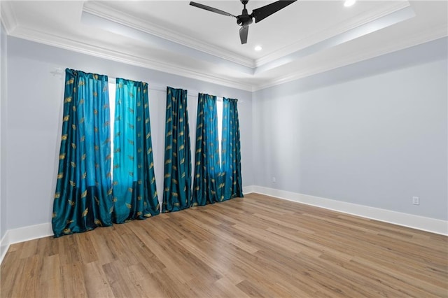 spare room with a tray ceiling, ceiling fan, light hardwood / wood-style flooring, and ornamental molding