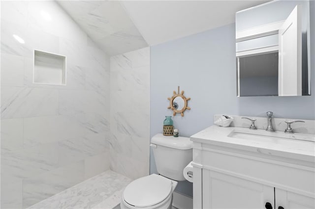 bathroom with a tile shower, vanity, and toilet