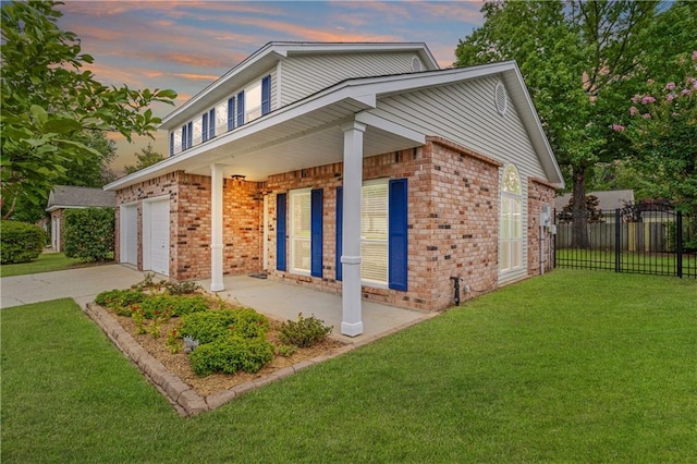 property exterior at dusk featuring brick siding, fence, a porch, a garage, and a yard