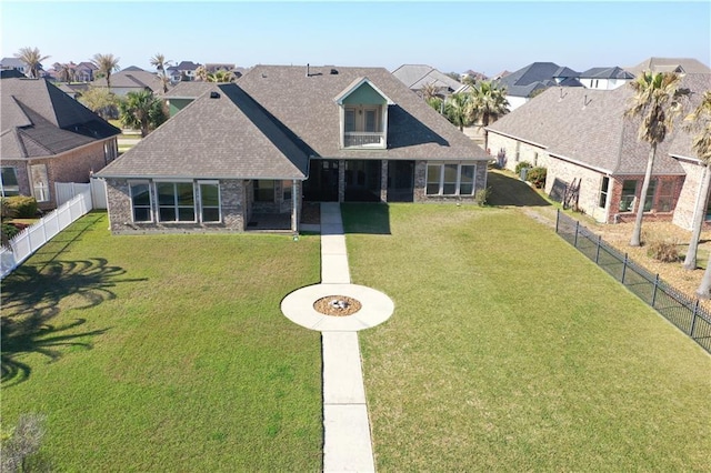 view of front of house with stone siding, a front yard, a fenced backyard, and a residential view