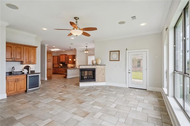 unfurnished living room with beverage cooler, baseboards, visible vents, ornamental molding, and stone finish floor