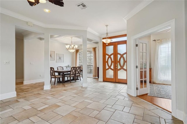 foyer with visible vents, a notable chandelier, stone tile flooring, crown molding, and baseboards