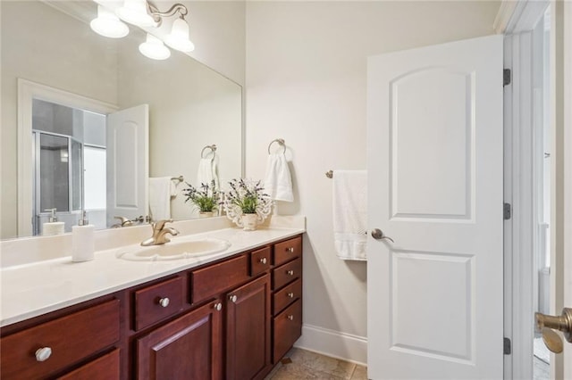 full bath with a notable chandelier, a shower stall, vanity, and baseboards