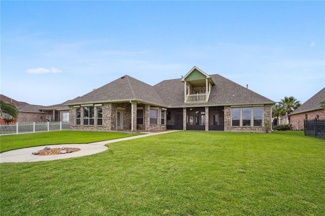 rear view of property with a yard, a balcony, and brick siding