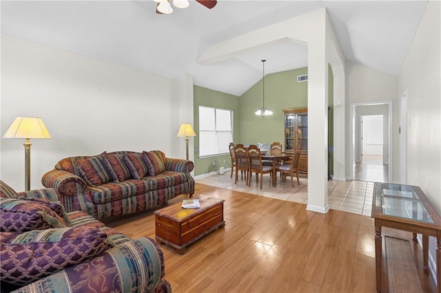 living room with vaulted ceiling with beams, light hardwood / wood-style floors, and ceiling fan with notable chandelier