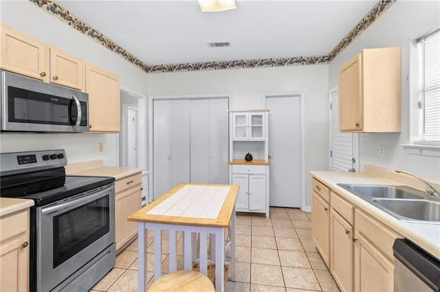 kitchen featuring light brown cabinetry, sink, light tile patterned floors, and appliances with stainless steel finishes