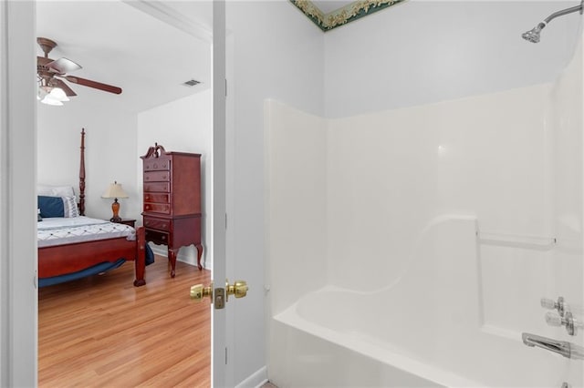 bathroom with ceiling fan, shower / bathtub combination, and wood-type flooring