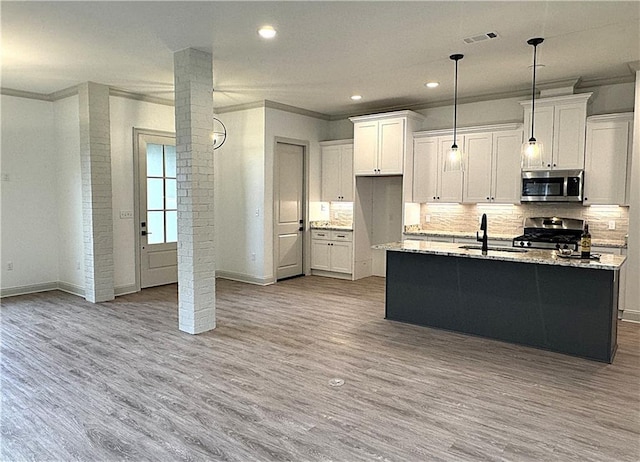 kitchen featuring appliances with stainless steel finishes, light hardwood / wood-style floors, white cabinetry, and sink