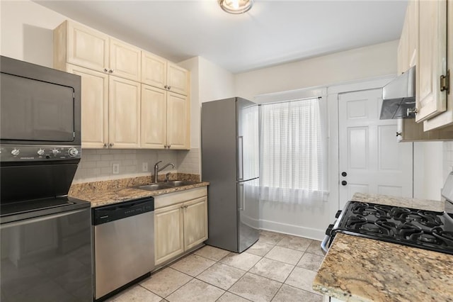 kitchen with light stone counters, extractor fan, stacked washer / dryer, and appliances with stainless steel finishes