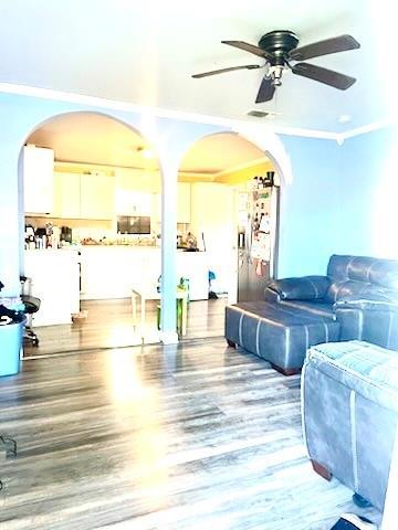 living room with hardwood / wood-style floors, ceiling fan, and crown molding