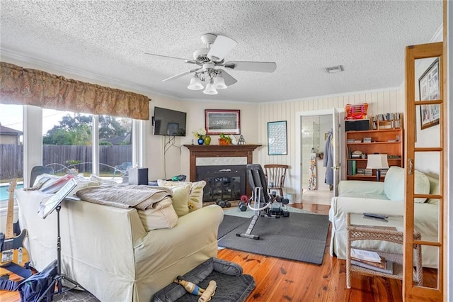 interior space featuring a textured ceiling, hardwood / wood-style flooring, ceiling fan, and crown molding