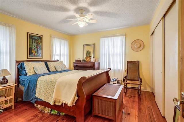 bedroom featuring hardwood / wood-style floors, a textured ceiling, a closet, and ceiling fan