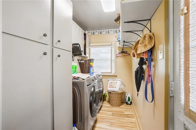 clothes washing area featuring cabinets, light wood-type flooring, and independent washer and dryer