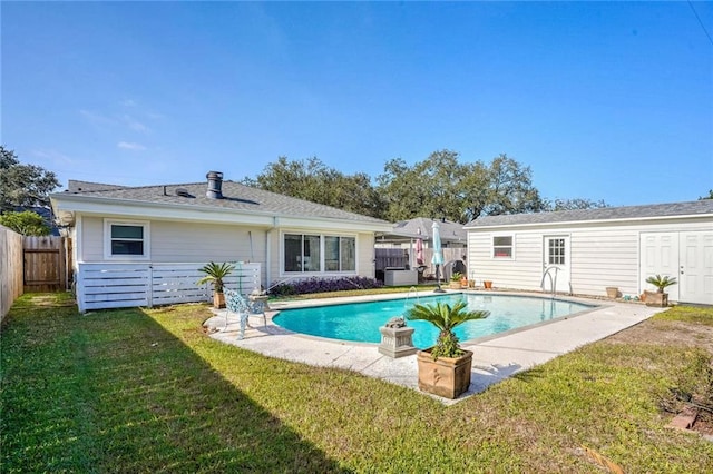 back of house with a fenced in pool, an outdoor structure, and a yard