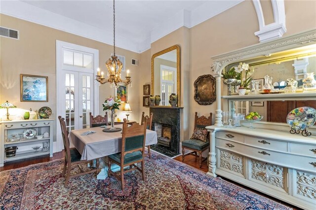918 Orleans Ave, New Orleans, LA 70116 - dining room with an inviting chandelier, wood finished floors, a high end fireplace, and visible vents