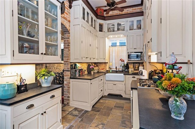 918 Orleans Ave, New Orleans, LA 70116 - kitchen featuring stainless steel microwave, a sink, dark countertops, a ceiling fan, and stone finish flooring