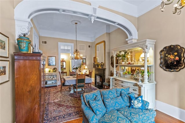 918 Orleans Ave, New Orleans, LA 70116 - living area with a notable chandelier, a fireplace, wood finished floors, baseboards, and visible vents