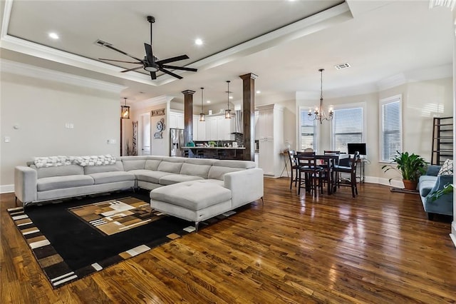 living room with dark hardwood / wood-style flooring, a raised ceiling, ornamental molding, and ceiling fan with notable chandelier