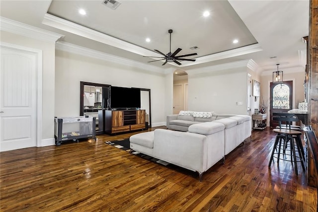 living room with dark hardwood / wood-style flooring, a tray ceiling, ceiling fan, and crown molding