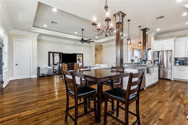 dining room featuring ceiling fan with notable chandelier, dark hardwood / wood-style flooring, crown molding, and a tray ceiling