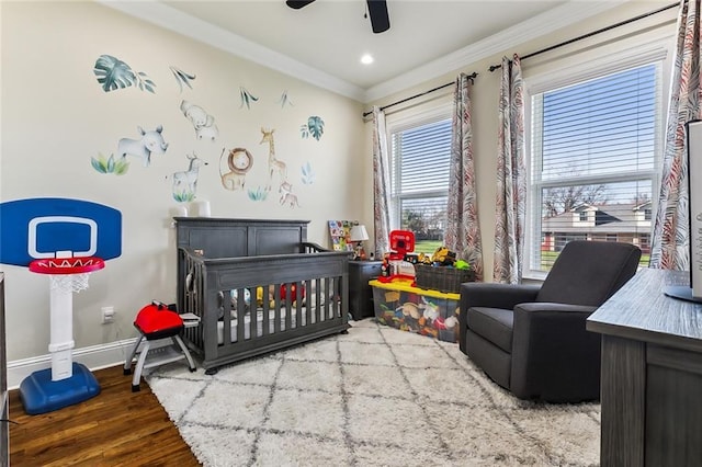 bedroom featuring hardwood / wood-style flooring, ceiling fan, a crib, and crown molding