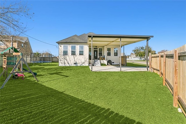 back of house with a trampoline, a playground, a patio, and a lawn