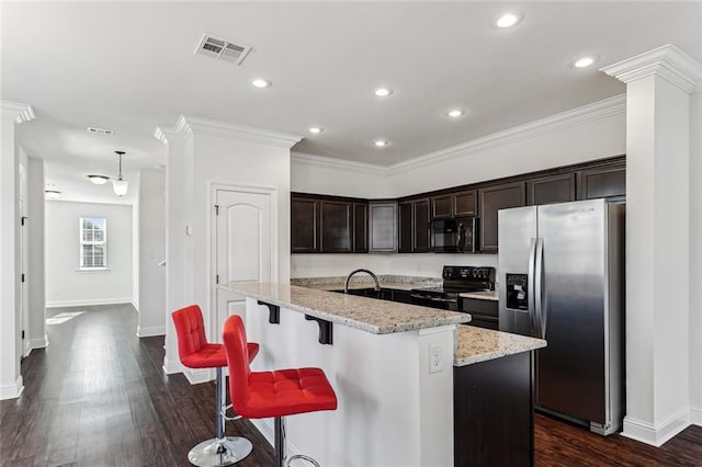 kitchen with hanging light fixtures, light stone counters, an island with sink, black appliances, and ornamental molding