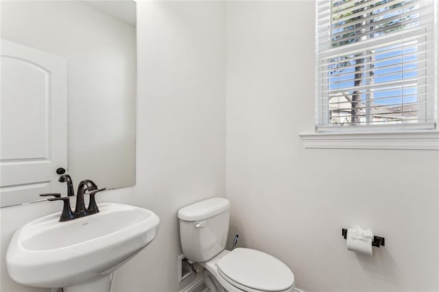 bathroom with a healthy amount of sunlight, toilet, and sink