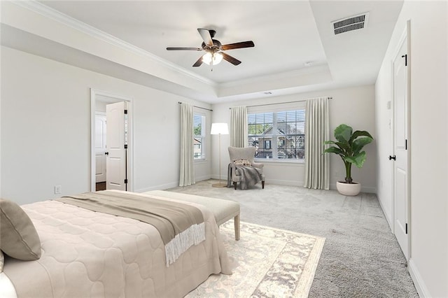 carpeted bedroom with ceiling fan, crown molding, and a tray ceiling