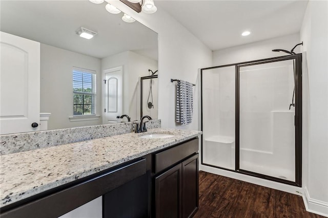 bathroom with wood-type flooring, vanity, and a shower with shower door