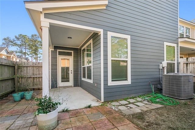 view of exterior entry with central air condition unit and a patio area