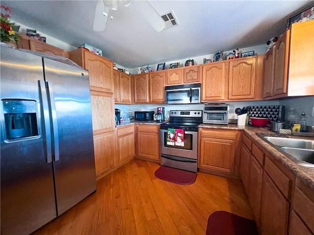 kitchen with ceiling fan, sink, stainless steel appliances, and light hardwood / wood-style flooring