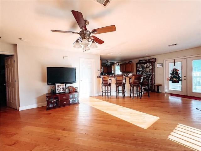 interior space with french doors, indoor bar, light hardwood / wood-style flooring, and ceiling fan