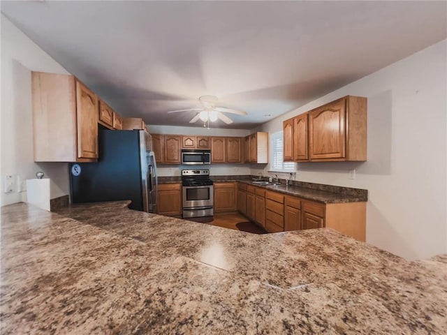 kitchen featuring ceiling fan, appliances with stainless steel finishes, a sink, and brown cabinets